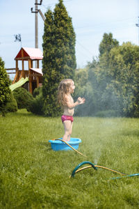 Little girl playing with water in the yard at home