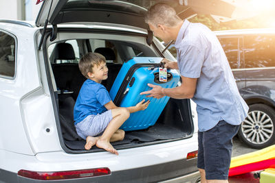 Rear view of father with son standing in car