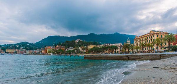 Scenic view of sea by buildings against sky