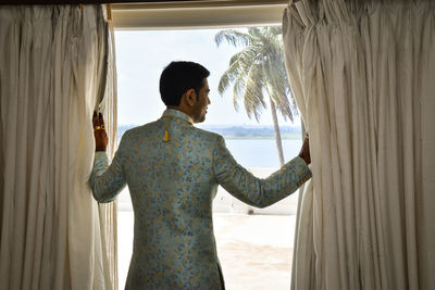 Rear view of woman standing by window