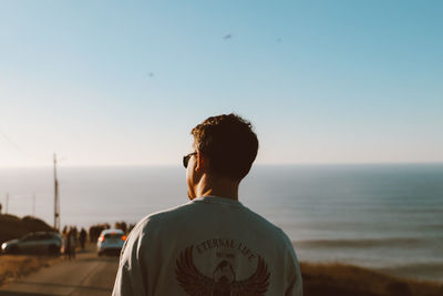 Rear view of man looking at sea against sky