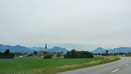 Road by landscape against sky in city