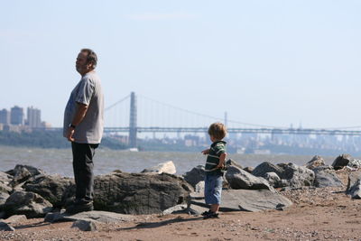 Senior man standing with grandson by river