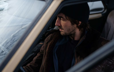 Man looking away while sitting in car