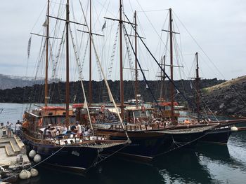 Sailboats moored in sea against sky