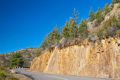 Road by mountain against clear blue sky