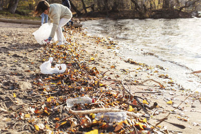 Female volunteer collecting plastic garbage by lake