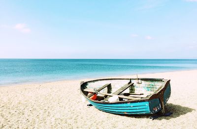 Boat moored on beach against sky