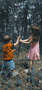 Siblings standing in forest