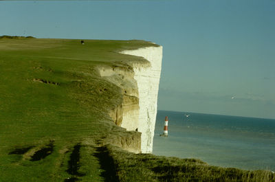 Scenic view of mountain cliff and sea against sky