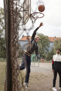 Teenager throwing ball into basketball hoop