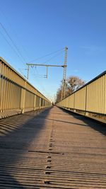 Surface level of footbridge against clear blue sky