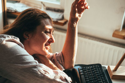 Side view of young woman using laptop at home