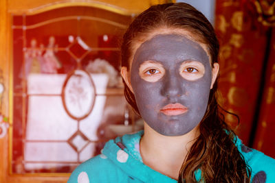 Close-up portrait of girl with facial mask at home