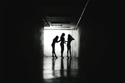 Silhouette female friends standing in tunnel