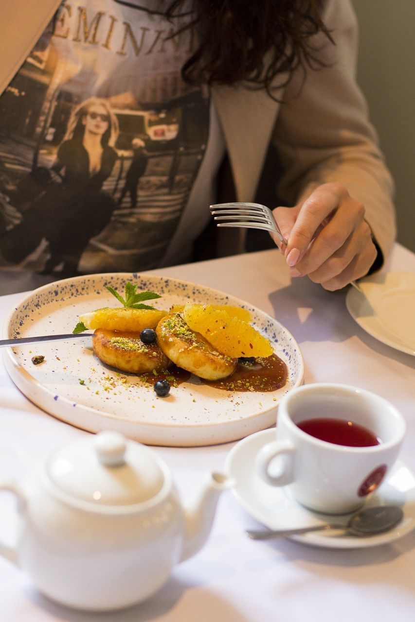 MIDSECTION OF WOMAN WITH COFFEE IN PLATE