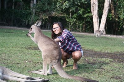 Smiling woman with kangaroo on grass