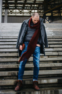 Man wearing warm clothing standing on steps outdoors