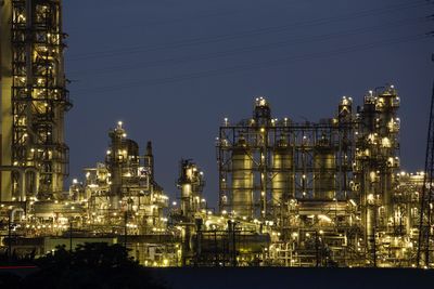 Illuminated factory against sky at night