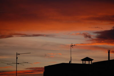 Low angle view of silhouette communications tower against sky during sunset