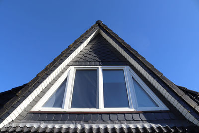 Open roof window in velux style with black roof tiles