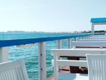 Chairs and table by sea against sky