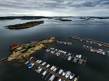 Boats moored at harbor against cloudy sky