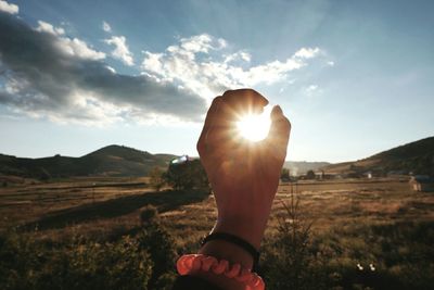 Close-up of woman with sun against sky during sunset