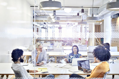 Business people having meeting at conference table seen through window