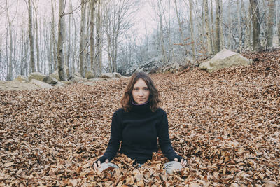 Woman enjoying autumn and catching falling yellow leaves