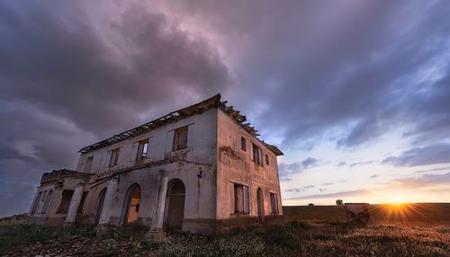 Low angle view of old building against sky during sunset