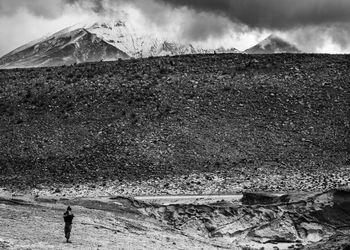 Man standing on field against snowcapped mountain