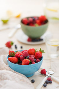 Assorted mix berry fruits in fruit bowl placed on white fabric