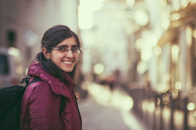 Portrait of smiling woman in city during winter