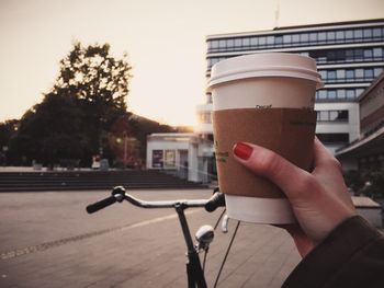 Cropped image of woman hand holding disposable coffee cup on city street