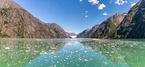 Scenic view of lake by mountains against blue sky