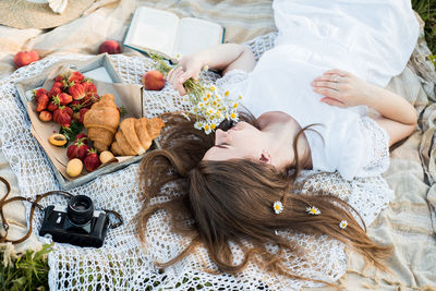 High angle view of woman lying on bed with food