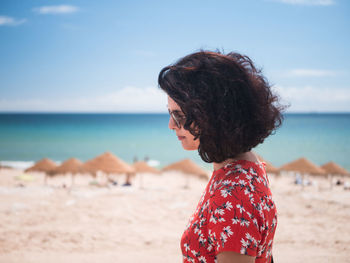 Midsection of woman at beach against sky