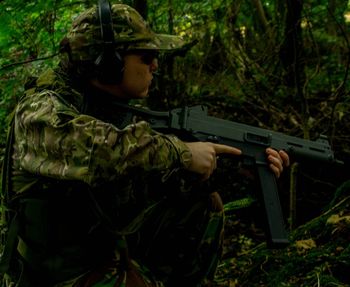 Army soldier aiming with rifle in forest