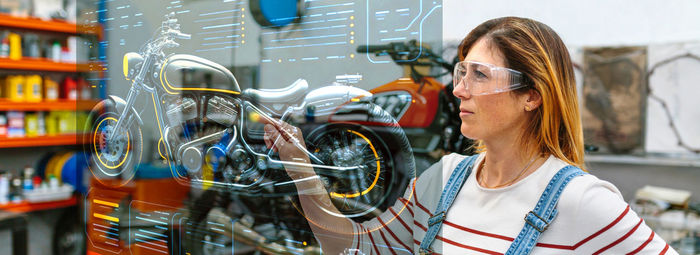 Female mechanic touching hud panel screen with augmented reality hologram to review motorcycle