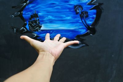 Cropped image of hand gesturing towards graffiti wall