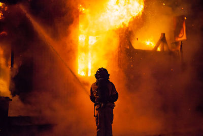 Rear view of firefighter at night