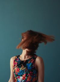 Redhead woman tossing hair against blue background