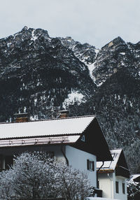 Snow covered houses by mountain against sky