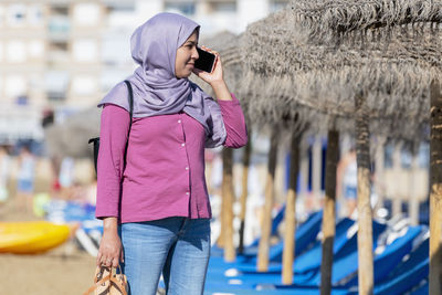 Side view of young woman standing against wall