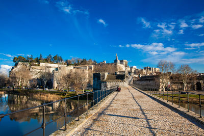 Buildings by river against blue sky