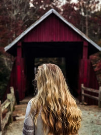 Rear view of young woman standing against barn