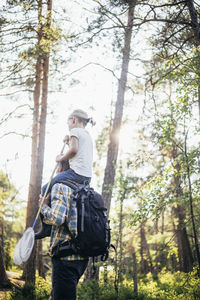 Low angle view of father carrying daughter on shoulder in forest