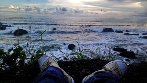 Low section of man on beach against sky