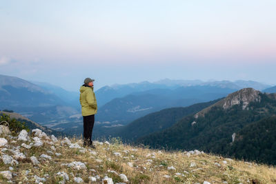 Rear view of man standing on mountain against sky